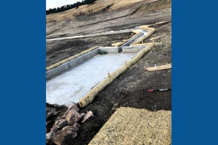 Erosion Control in Black Forest Colorado, installing straw waddles around the pond concrete structures so that the dirt does not end up in the concrete areas.