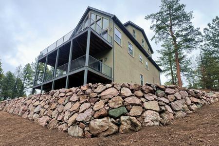 Retaining wall in Florissant, Colorado. Installed a series of boulder retaining walls to level off the area behind the deck and to protect the deck pillars