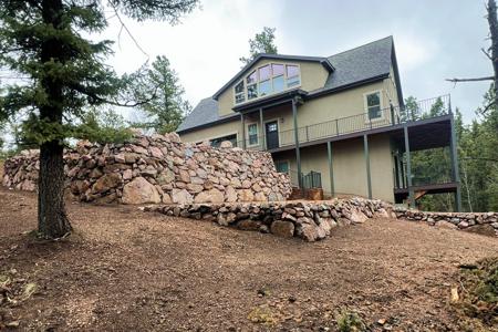 Retaining wall in Florissant, Colorado. Installed a series of boulder walls to create an entrance into the garage of this new home build.